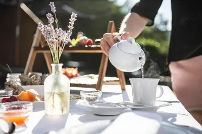 a person pouring coffee into a cup on a table at Chalet Grumer Suites&Spa in Soprabolzano