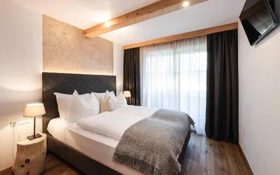a bedroom with a large bed and a window at Chalet Grumer Suites&Spa in Soprabolzano