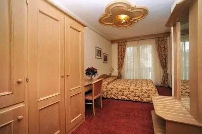 a hotel room with a bed and a desk and a bedroom at Hotel Europa in Moena