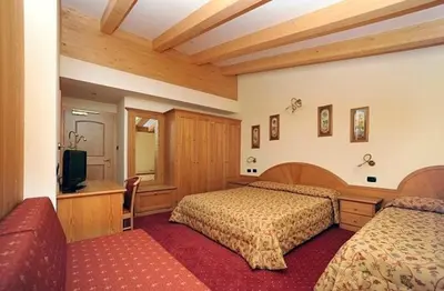 a hotel room with two beds and a television at Hotel Europa in Moena