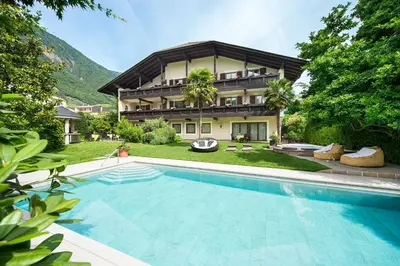 a house with a swimming pool in front of a house at Hotel Verena in Lana