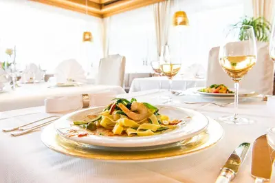 a plate of food on a table with wine glasses at Hotel Verena in Lana