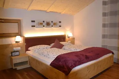 a bedroom with a large bed with a wooden headboard at Residence Talblick in San Leonardo in Passiria