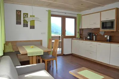 a kitchen and living room with a table and a couch at Residence Talblick in San Leonardo in Passiria