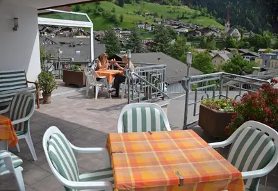a woman sitting at a table on a patio at Residence Talblick in San Leonardo in Passiria