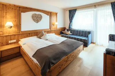 a bedroom with a large bed and a couch at Tirolerhof in San Leonardo in Passiria