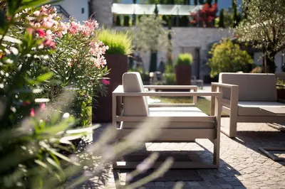 two white chairs sitting on a patio with flowers at Felderer Boutiquehotel B&B in Caldaro