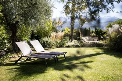 two chairs sitting on the grass in a garden at Felderer Boutiquehotel B&B in Caldaro