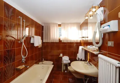 a large bathroom with a jacuzzi tub with chairs at Park Hotel Villa Trunka Lunka in Cavalese