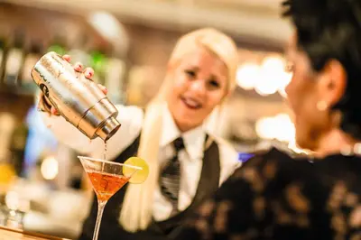 a woman pouring a drink into a martini glass at Hotel Panorama in Schenna