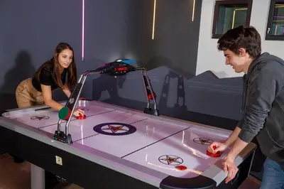 a man and a woman standing next to a table with a video game at Hotel Panorama in Schenna