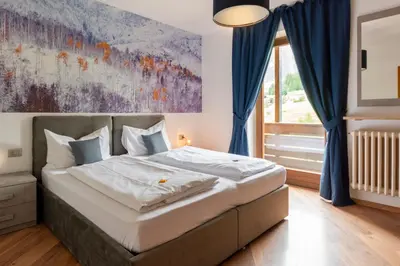 a bedroom with a bed with a painting on the wall at Kyrr Smart Mountain Retreat in Moena