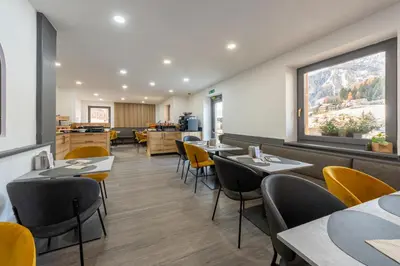 a restaurant with tables and chairs and a window at Kyrr Smart Mountain Retreat in Moena