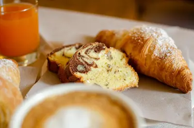 a plate of bread and croissants and a glass of orange juice at Kyrr Smart Mountain Retreat in Moena