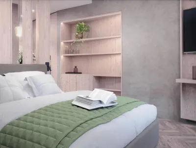 a bedroom with a bed with a green blanket and books at Hotel Garni Nachtigall in Schenna