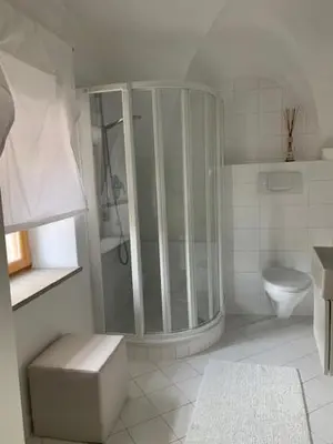 a white bathroom with a shower and a toilet at Hof Am Bach in Caldaro