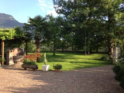 a park with trees and a lawn with plants at On the River in Laives