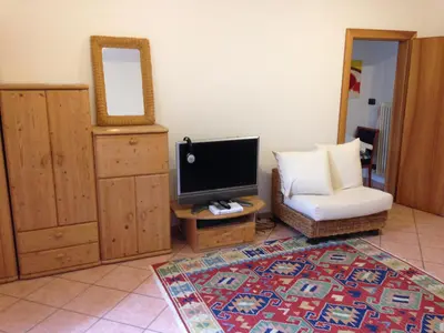 a living room with a tv and a chair and a mirror at On the River in Laives
