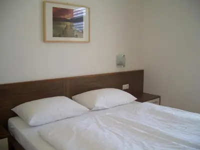 a bed with two white pillows and a picture on the wall at Apartments Tauberhof in Naz-Sciaves