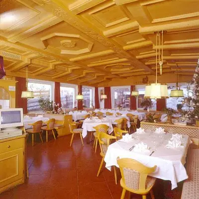 a dining room with white tables and yellow chairs at Hotel Scoiattolo in Selva di Val Gardena