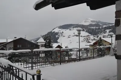 a snow covered fence with a mountain in the background at Hotel Scoiattolo in Selva di Val Gardena