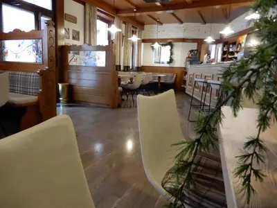 a restaurant with white chairs and a table and a christmas tree at Hotel Al Cervo in Tesero