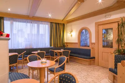 a restaurant with tables and chairs and a window at Hotel Al Cervo in Tesero