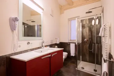a bathroom with a sink and a shower and a toilet at Hotel Al Cervo in Tesero
