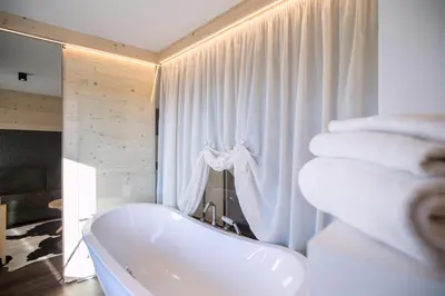 a bathroom with a tub and a pile of towels at Hotel Al Cervo in Tesero