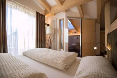 a bedroom with two beds and a large window at Hotel Al Cervo in Tesero
