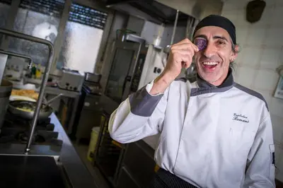 a chef talking on a cell phone in a kitchen at Hotel Al Cervo in Tesero