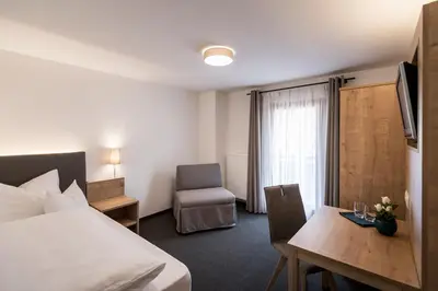 a hotel room with a bed and a desk and a chair at Garni Grünau in San Martino