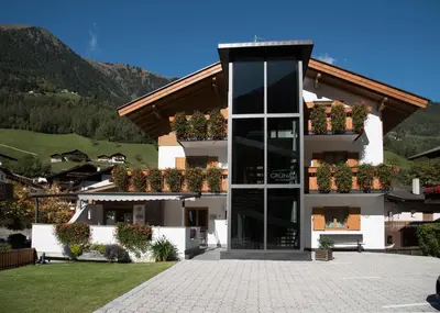 a white building with potted plants on it at Garni Grünau in San Martino