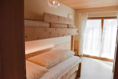 a bedroom with a bed with a wooden shelf at Tschafingerhof in Vipiteno