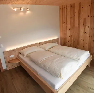 a bed in a room with a wooden wall at Tschafingerhof in Vipiteno