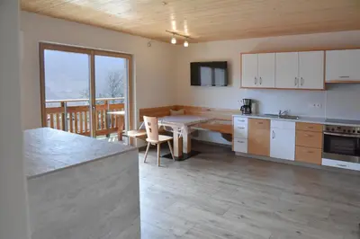 a kitchen with white cabinets and a table with a dining room at Tschafingerhof in Vipiteno