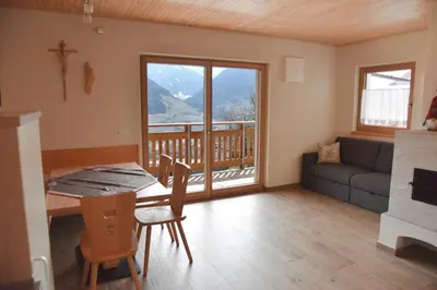 a living room with a table and chairs and a balcony at Tschafingerhof in Vipiteno