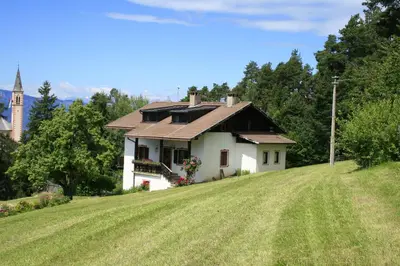 a small white house on a hill with a church at Finhäusl in Aldino