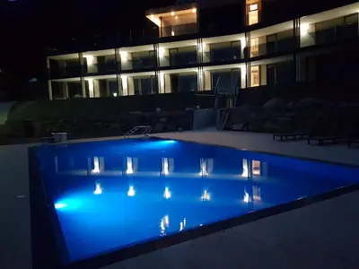 a swimming pool in front of a building at night at Aparthotel Malga in Caldaro