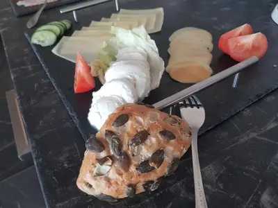a plate of food with sushi and cheese and a fork at Aparthotel Malga in Caldaro