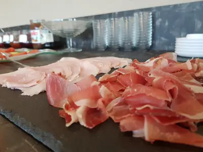 a bunch of ham on a counter in a kitchen at Aparthotel Malga in Caldaro