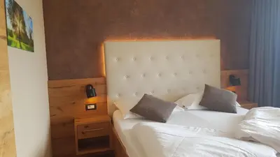 a bedroom with a white bed with two pillows at Aparthotel Malga in Caldaro