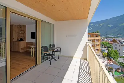 a balcony of a house with a table and chairs at Hotel Nocturnes in Naturno