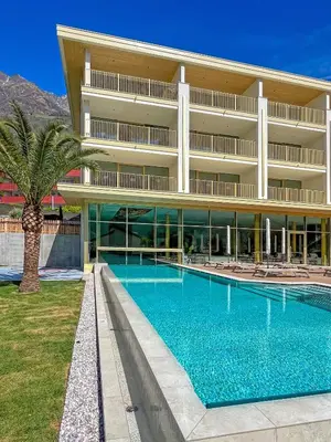 a large building with a swimming pool and a palm tree at Hotel Nocturnes in Naturno