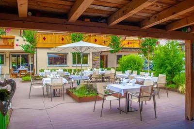 a restaurant with tables and chairs and an umbrella at Hotel Mehrhauser in Nalles