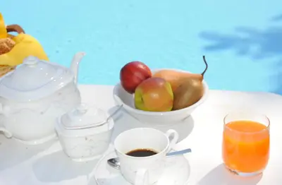 a table with a cup of coffee and a bowl of apples at Hotel Mehrhauser in Nalles