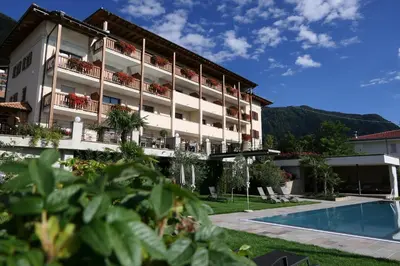 a hotel with a swimming pool and mountains in the background at B & B Gurterhof in Schenna