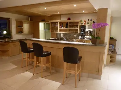 a kitchen with a bar with four chairs at it at B & B Gurterhof in Schenna