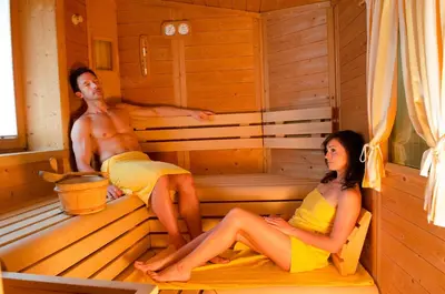 a man and a woman sitting in a sauna at Pension Felseneck in San Leonardo in Passiria