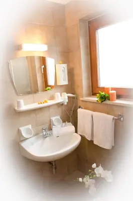 a bathroom with a sink and a mirror and towels at Pension Felseneck in San Leonardo in Passiria